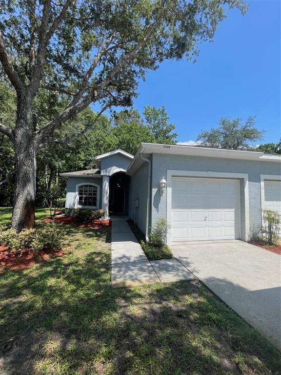 A single-story house with a light blue exterior, a white garage door, and a walkway — 12509 CAVALIER COURT, HUDSON, FL