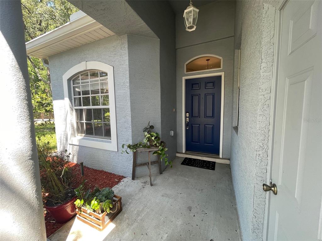 A blue front door is set in a gray stucco exterior with a concrete porch — 12509 CAVALIER COURT, HUDSON, FL