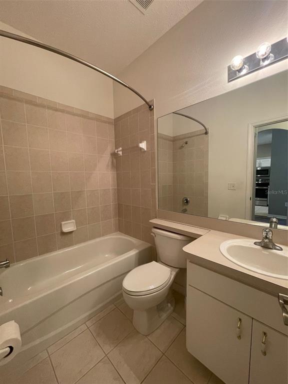 A bathroom features a tiled shower-tub combination, a white toilet, and a single-sink vanity — 12509 CAVALIER COURT, HUDSON, FL