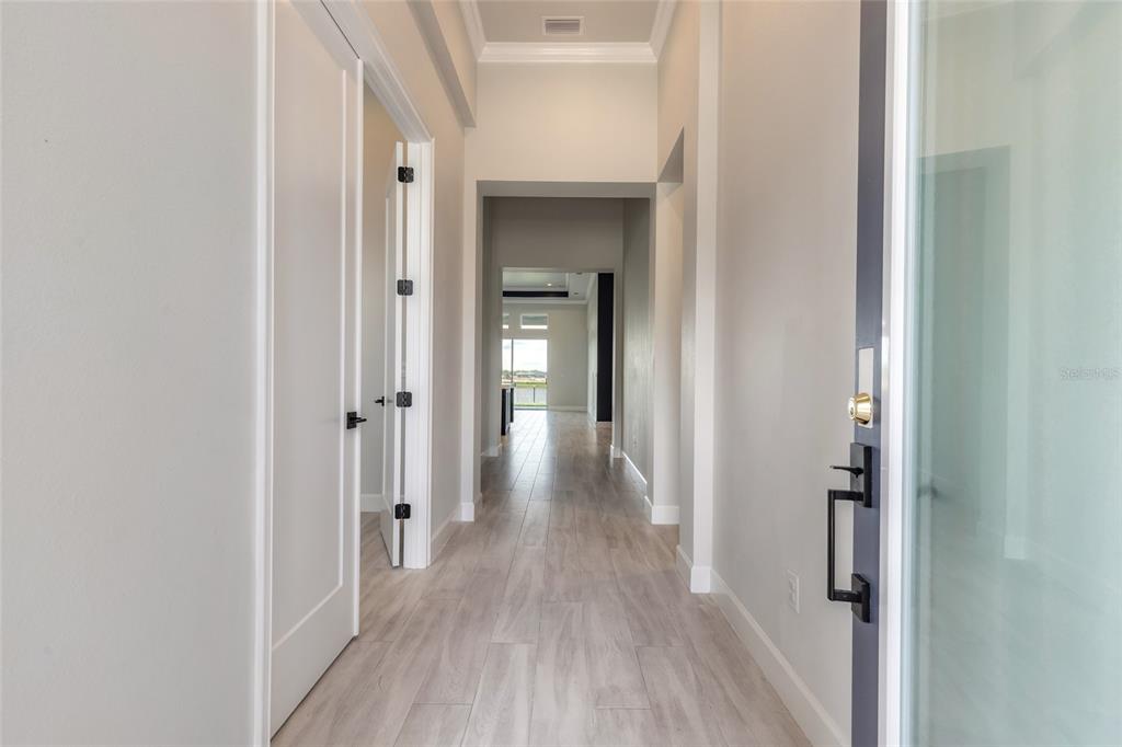 A bright hallway with light wood-look tile flooring leads toward an open living area — 321 AQUAMARINE WAY, DAYTONA BEACH, FL