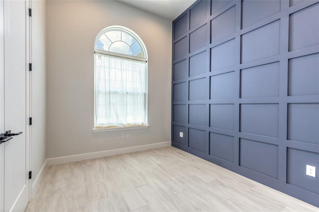 A room with light wood-look flooring, a large arched window, and a blue paneled wall — 321 AQUAMARINE WAY, DAYTONA BEACH, FL