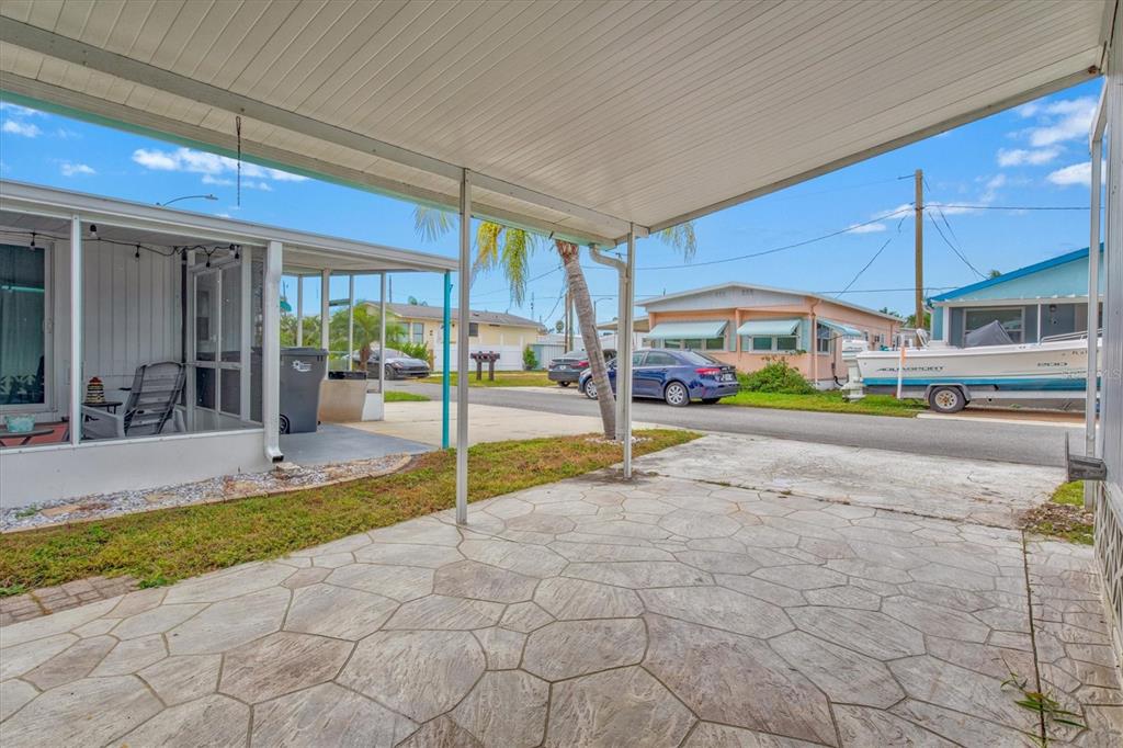 A covered concrete patio with a stone pattern overlooks a residential street with parked cars — 3831 115TH STREET COURT W, BRADENTON, FL
