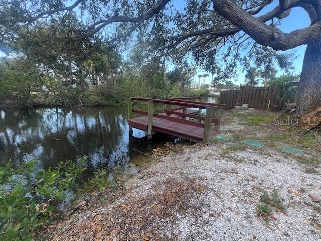 A wooden footbridge extends over a small canal near a large tree and wooden fence — 321 RAVENNA STREET N, NOKOMIS, FL