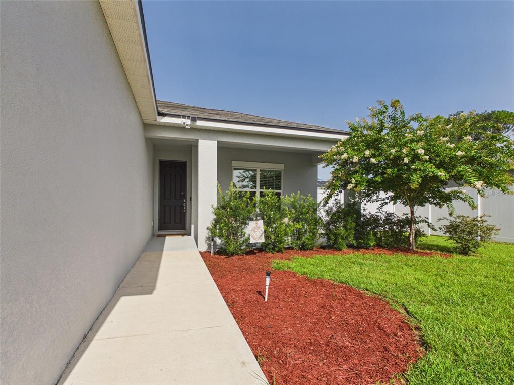 A concrete walkway leads to the front entrance of a house with a landscaped yard — 15110 SW 43RD AVENUE ROAD, OCALA, FL