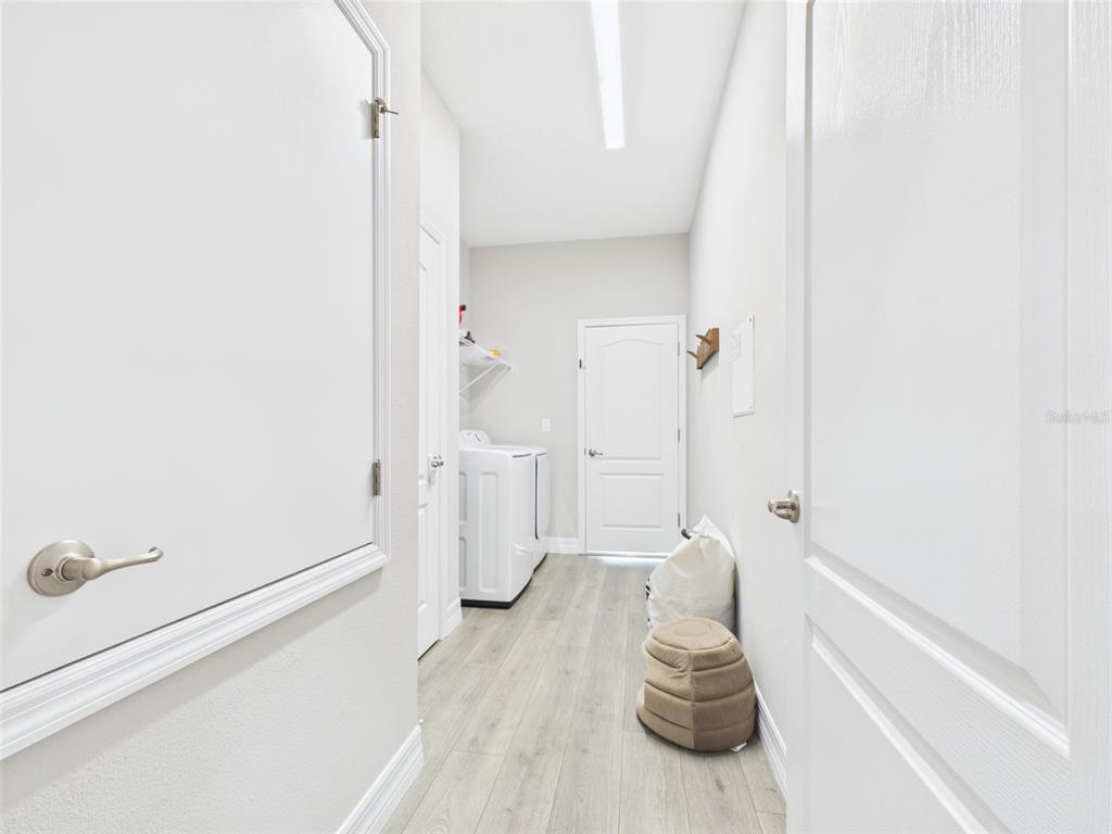 A laundry room with white walls, light wood-look flooring, and a white washer and dryer — 15110 SW 43RD AVENUE ROAD, OCALA, FL