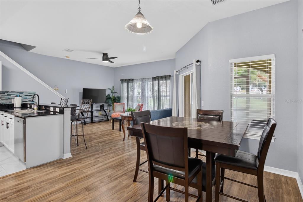 An open-concept dining and living area features wood-look flooring, a kitchen island, and sliding doors — 10844 DRAGONWOOD DRIVE, TAMPA, FL