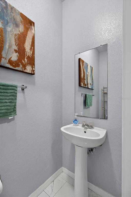 A small bathroom features a pedestal sink, a wall mirror, and a green hand towel — 10844 DRAGONWOOD DRIVE, TAMPA, FL