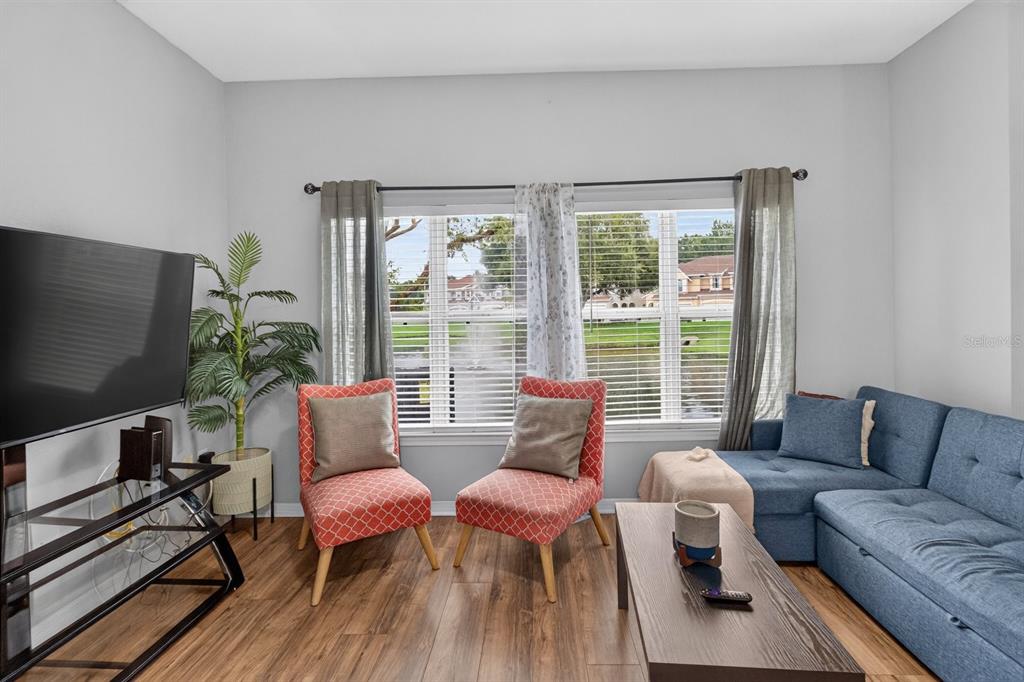 A living room features a blue sectional, two patterned chairs, a coffee table, and window views — 10844 DRAGONWOOD DRIVE, TAMPA, FL