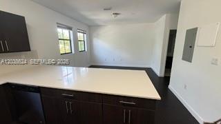 A kitchen island with a white countertop faces an open living area with dark flooring — 15500 SW 136th St. # 211, Miami FL 33196, MIAMI, FL