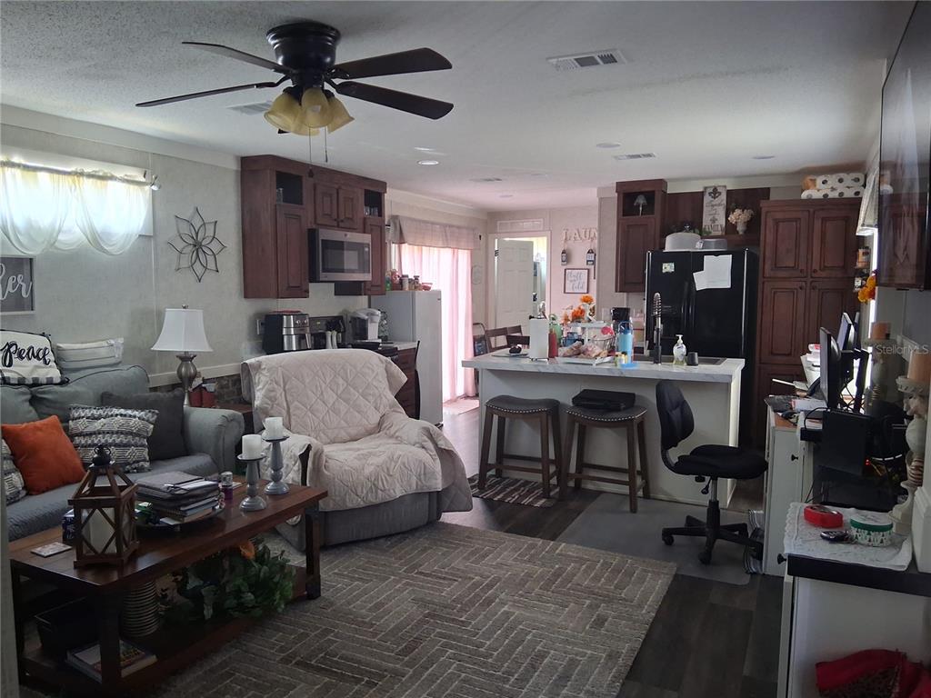 A kitchen features dark wood cabinets, a white island with a sink, and black appliances — 9170 DAN LYNN STREET, BROOKSVILLE, FL
