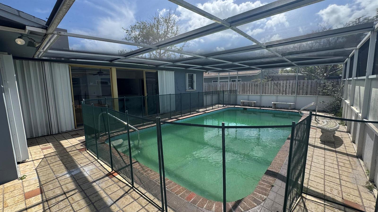 A screened-in patio features a rectangular swimming pool enclosed by a removable safety fence — 5401 W Park Road, Hollywood FL 33021, HOLLYWOOD, FL