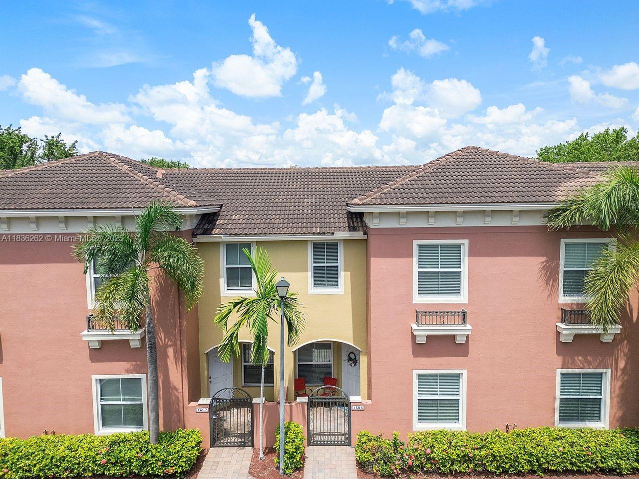 A two-story peach-colored townhouse exterior features two gated entryways and palm trees — 2851 W Prospect Rd # 1306, Tamarac FL 33309, TAMARAC, FL