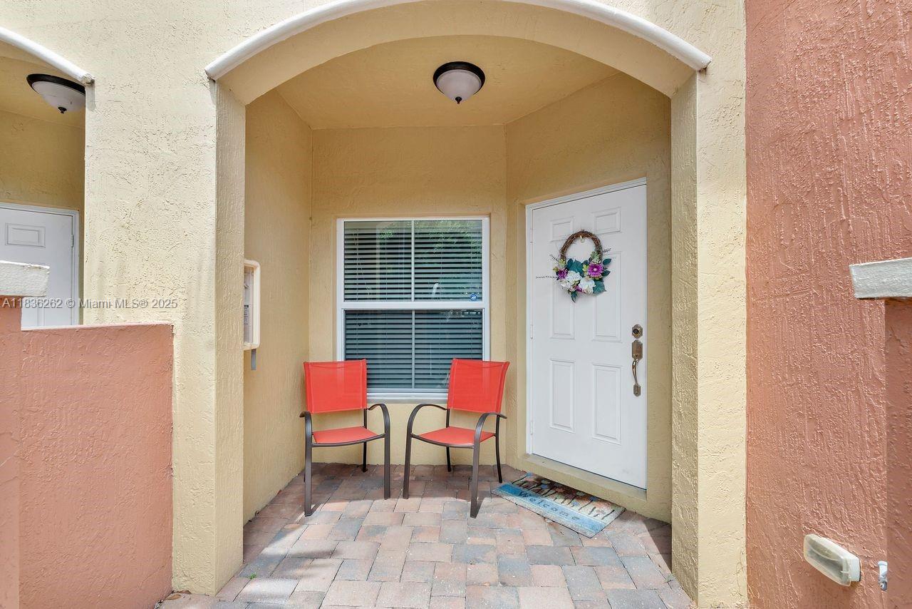 An exterior entryway features a white door, a window, and two orange chairs on pavers — 2851 W Prospect Rd # 1306, Tamarac FL 33309, TAMARAC, FL