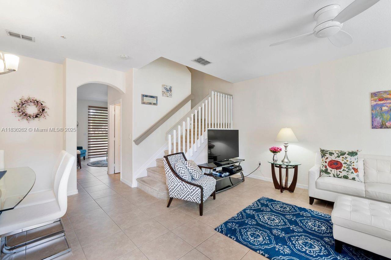 A living room features tile flooring, a staircase, a white sofa, and a patterned armchair — 2851 W Prospect Rd # 1306, Tamarac FL 33309, TAMARAC, FL