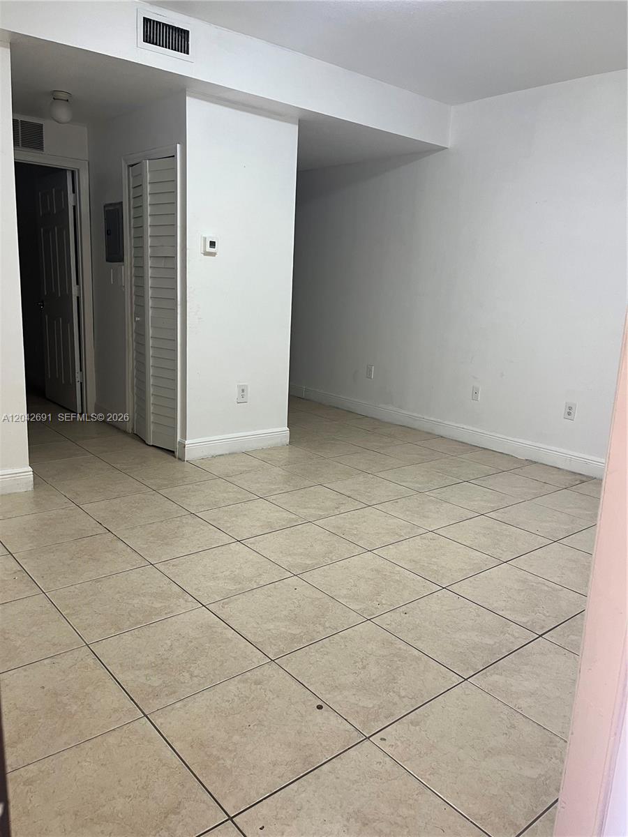 An empty room features white walls, beige tile flooring, and a white louvered closet door — 2185 NW 16th Ter # 10, Miami FL 33125, MIAMI, FL