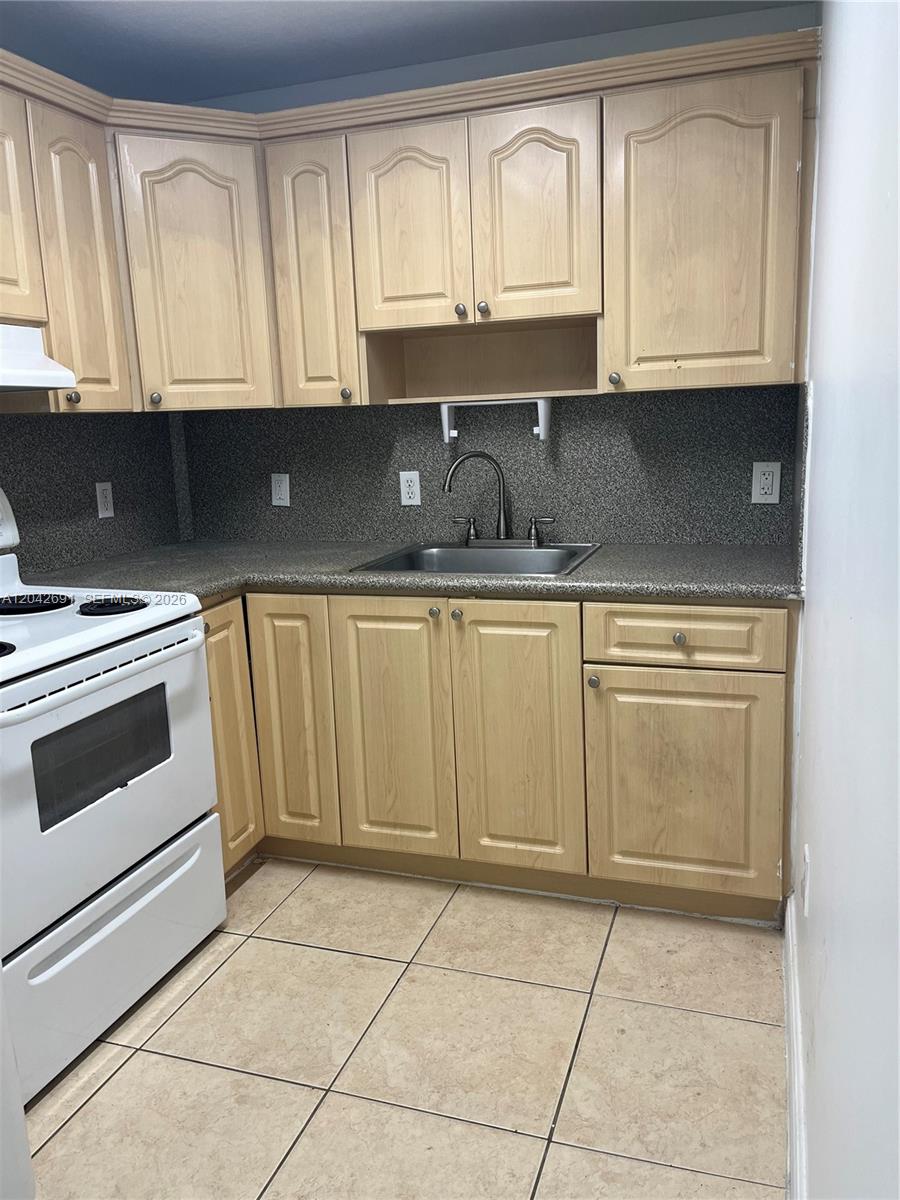 A kitchen features light wood cabinets, a speckled gray countertop, and a white stove — 2185 NW 16th Ter # 10, Miami FL 33125, MIAMI, FL