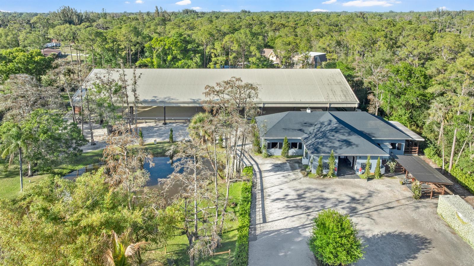 An aerial view shows a large metal-roofed barn next to a house and pond — 15161 Collecting Canal Road, FL 33470, FL