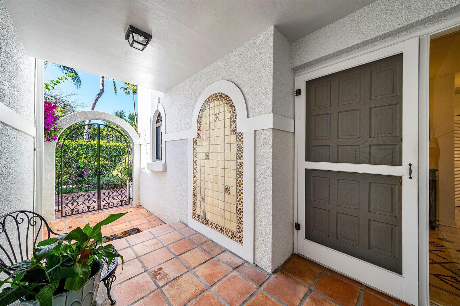 A covered patio features terracotta tile flooring, a decorative tiled wall niche, and a metal gate — 5560 N Ocean Boulevard # A, Ocean Ridge FL 33435, OCEAN RIDGE, FL