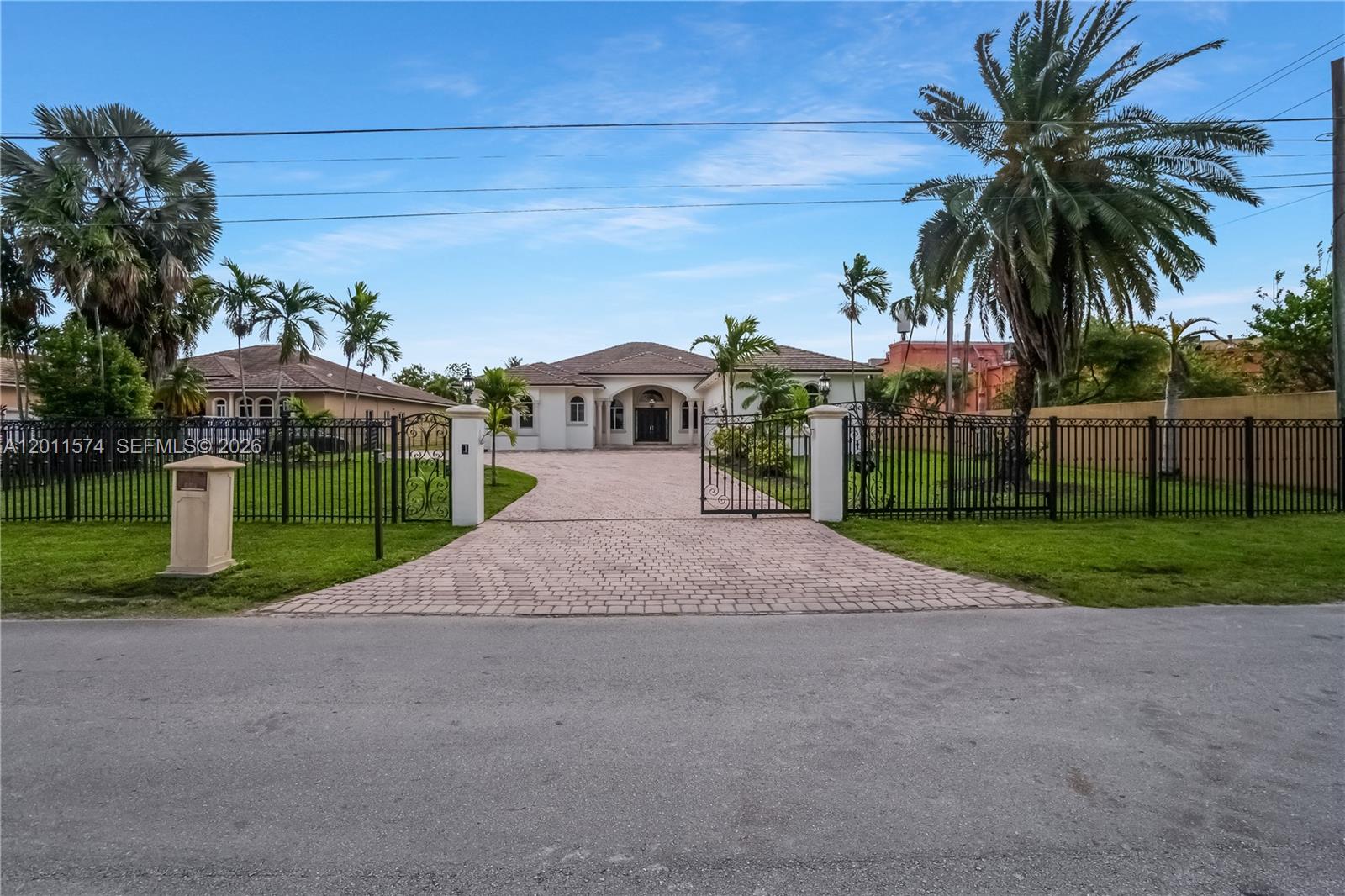 A single-story house with a paved driveway sits behind a black metal gate and fence — 4025 SW 128th Ave, Miami FL 33175, MIAMI, FL