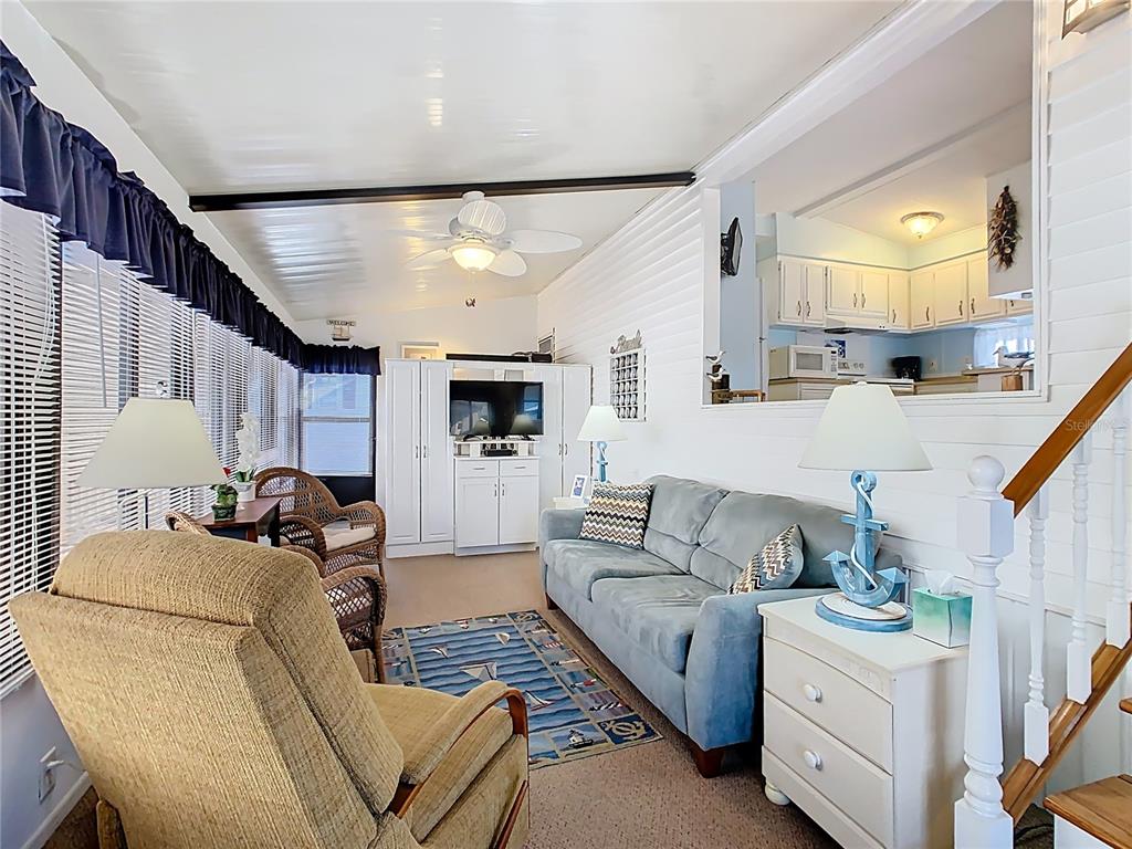 A sunroom features a blue sofa, a beige recliner, and a view into the kitchen — 9000 US HWY 192 UNIT 293, CLERMONT, FL
