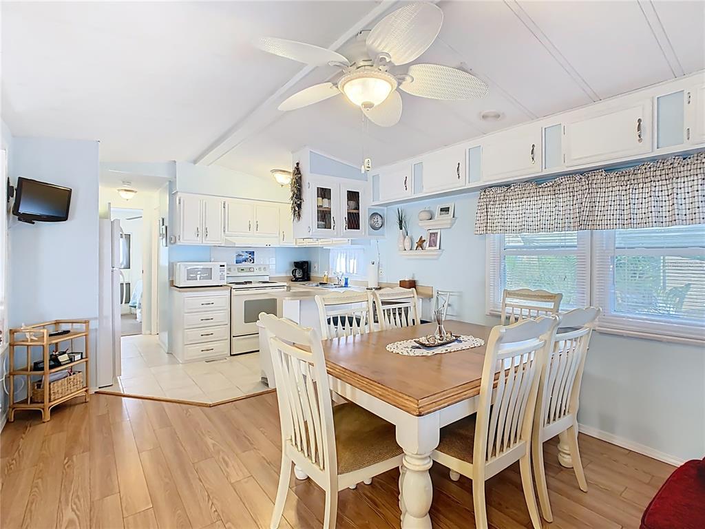 A dining area with a wooden table and white chairs sits adjacent to a kitchen — 9000 US HWY 192 UNIT 293, CLERMONT, FL