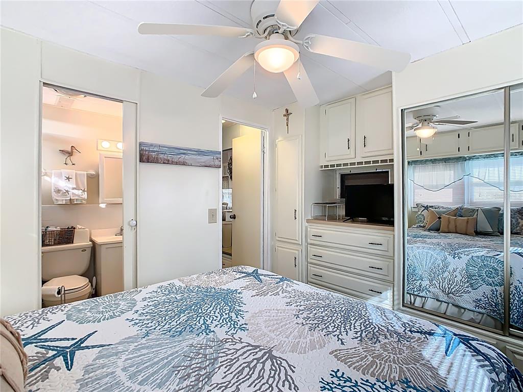 A bedroom features a ceiling fan, a dresser with a television, and an attached bathroom — 9000 US HWY 192 UNIT 293, CLERMONT, FL