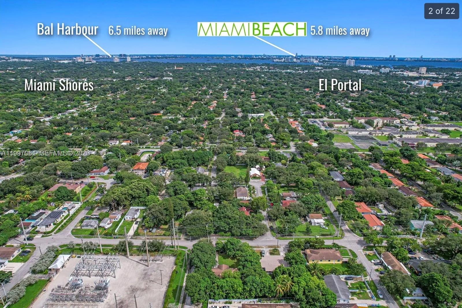 An aerial view shows a residential neighborhood with dense trees, streets, and distant coastal skylines — 9156 NW 5th Ave, Miami FL 33150, MIAMI, FL