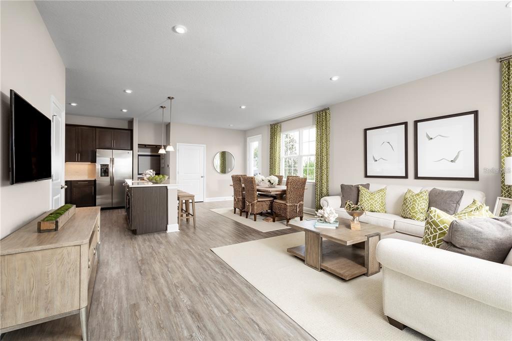 An open-concept living and dining area features light wood flooring, neutral walls, and modern furniture — 6712 CEDAR LANDING CIRCLE, LEESBURG, FL