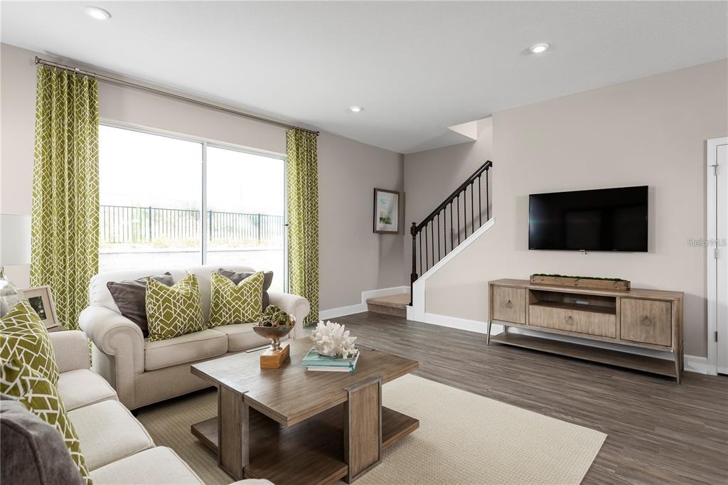A living room features a beige sofa, wooden coffee table, media console, and a staircase — 6712 CEDAR LANDING CIRCLE, LEESBURG, FL