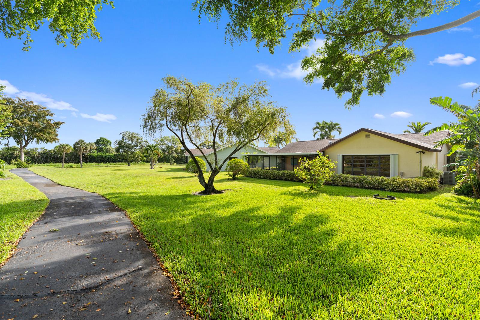 A paved path leads through a grassy yard toward a single-story house with trees — 18051 S 104th Ter Terrace S, Boca Raton FL 33498, BOCA RATON, FL