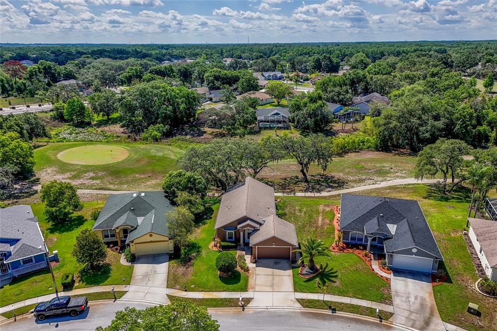 An aerial view shows three suburban houses with garages and driveways facing a golf course — 13253 GOLF RIDGE PLACE, HUDSON, FL