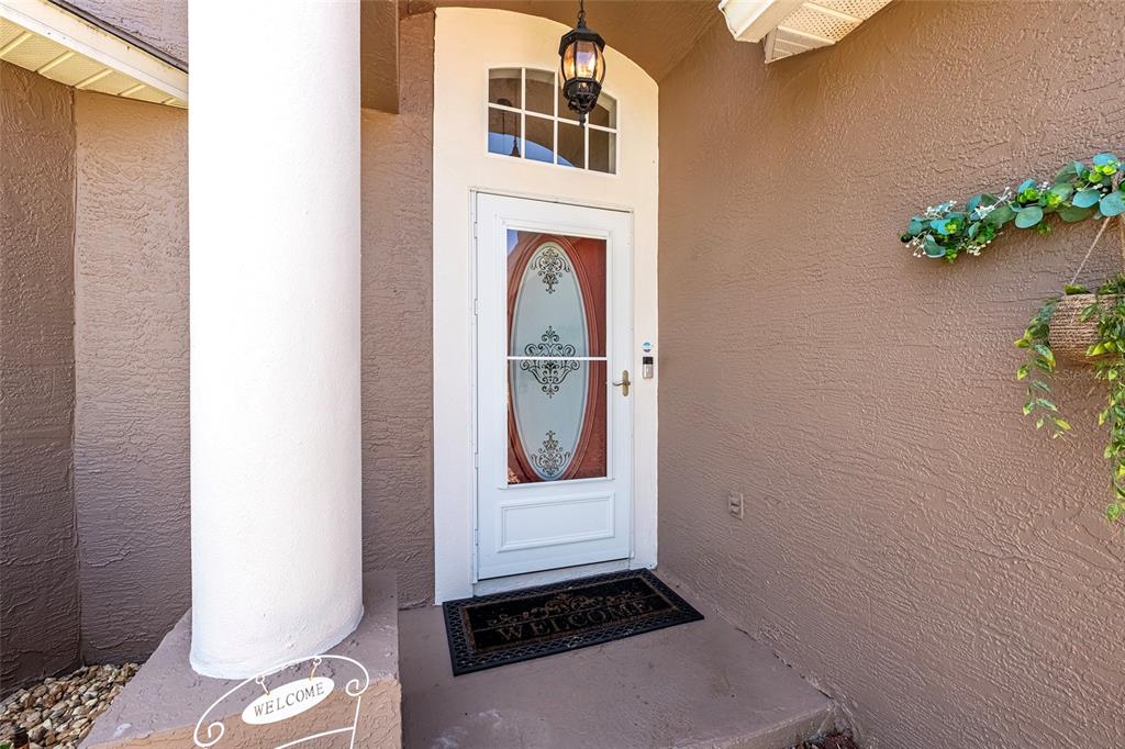 A front entryway features a white door with a decorative glass insert and a welcome mat — 13253 GOLF RIDGE PLACE, HUDSON, FL