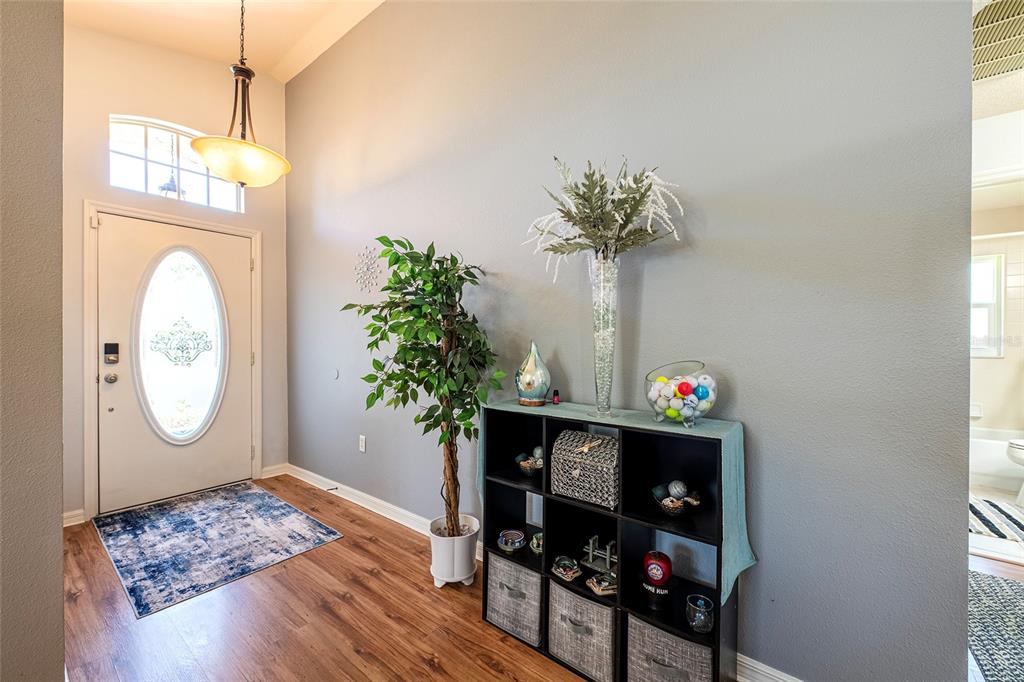 An entryway features wood-look flooring, a white front door with a glass insert, and shelving — 13253 GOLF RIDGE PLACE, HUDSON, FL