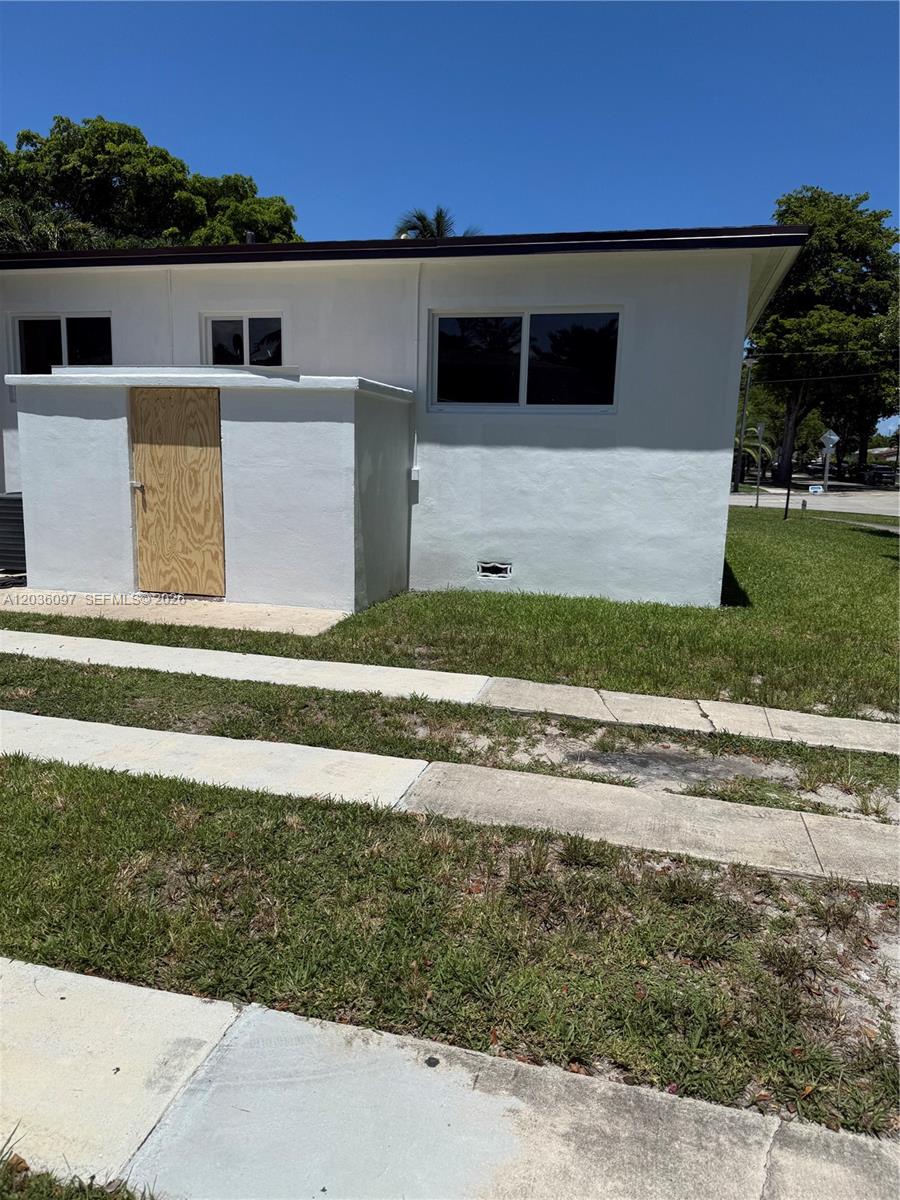 The exterior of a white house features a plywood door and a concrete driveway — 1460 SW 65th Ave, West Miami FL 33144, WEST MIAMI, FL