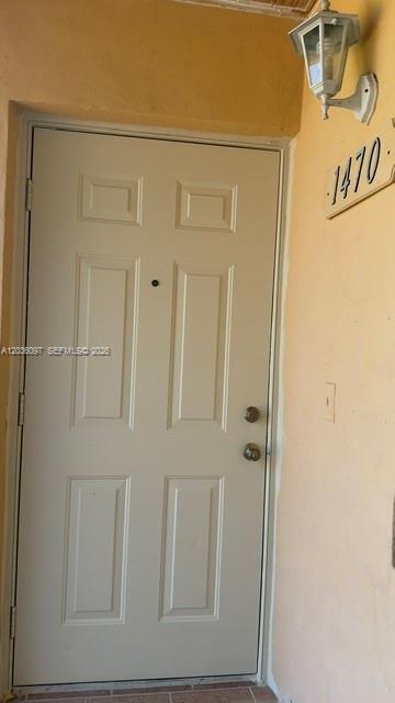 A white six-panel entry door with a peephole and two locks sits in a yellow wall — 1460 SW 65th Ave, West Miami FL 33144, WEST MIAMI, FL