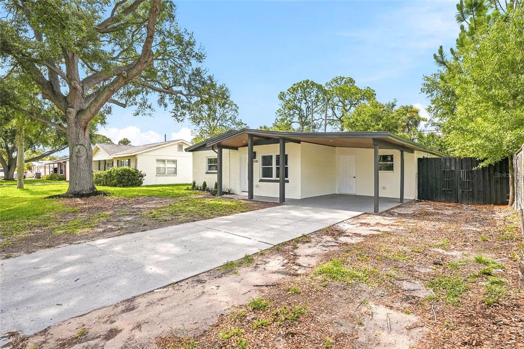A single-story house with a painted brick exterior, a flat roof, and a concrete carport — 8118 TANGLEWOOD LANE, TAMPA, FL
