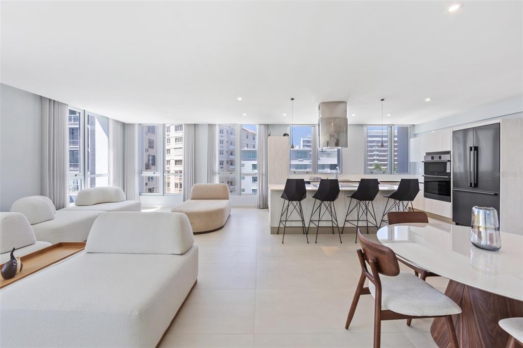 A modern open-concept living and dining area features white furniture, tile floors, and kitchen island — 14 CALLE DELCASSE UNIT 703, SAN JUAN, PR
