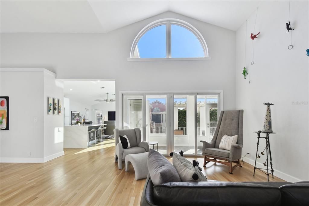 A living room with vaulted ceilings, a large arched window, and sliding glass doors — 21 CRESCENT PLACE S, ST PETERSBURG, FL