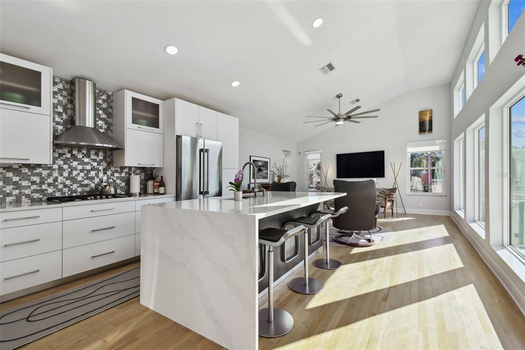 A modern kitchen features white cabinets, a marble-topped island, and stainless steel appliances — 21 CRESCENT PLACE S, ST PETERSBURG, FL