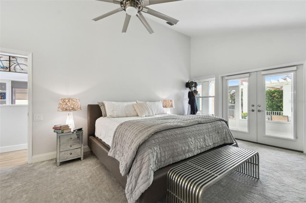 A bedroom features a bed with a gray quilt, a ceiling fan, and glass doors — 21 CRESCENT PLACE S, ST PETERSBURG, FL