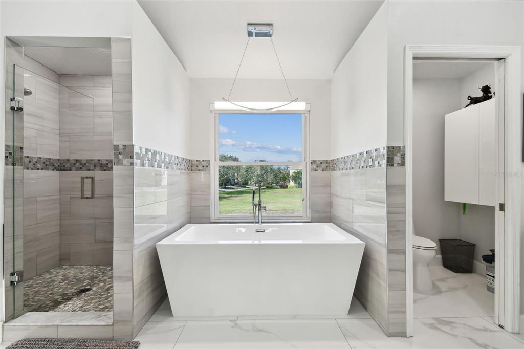 A modern bathroom features a freestanding tub, a glass-enclosed shower, and a private toilet area — 21 CRESCENT PLACE S, ST PETERSBURG, FL