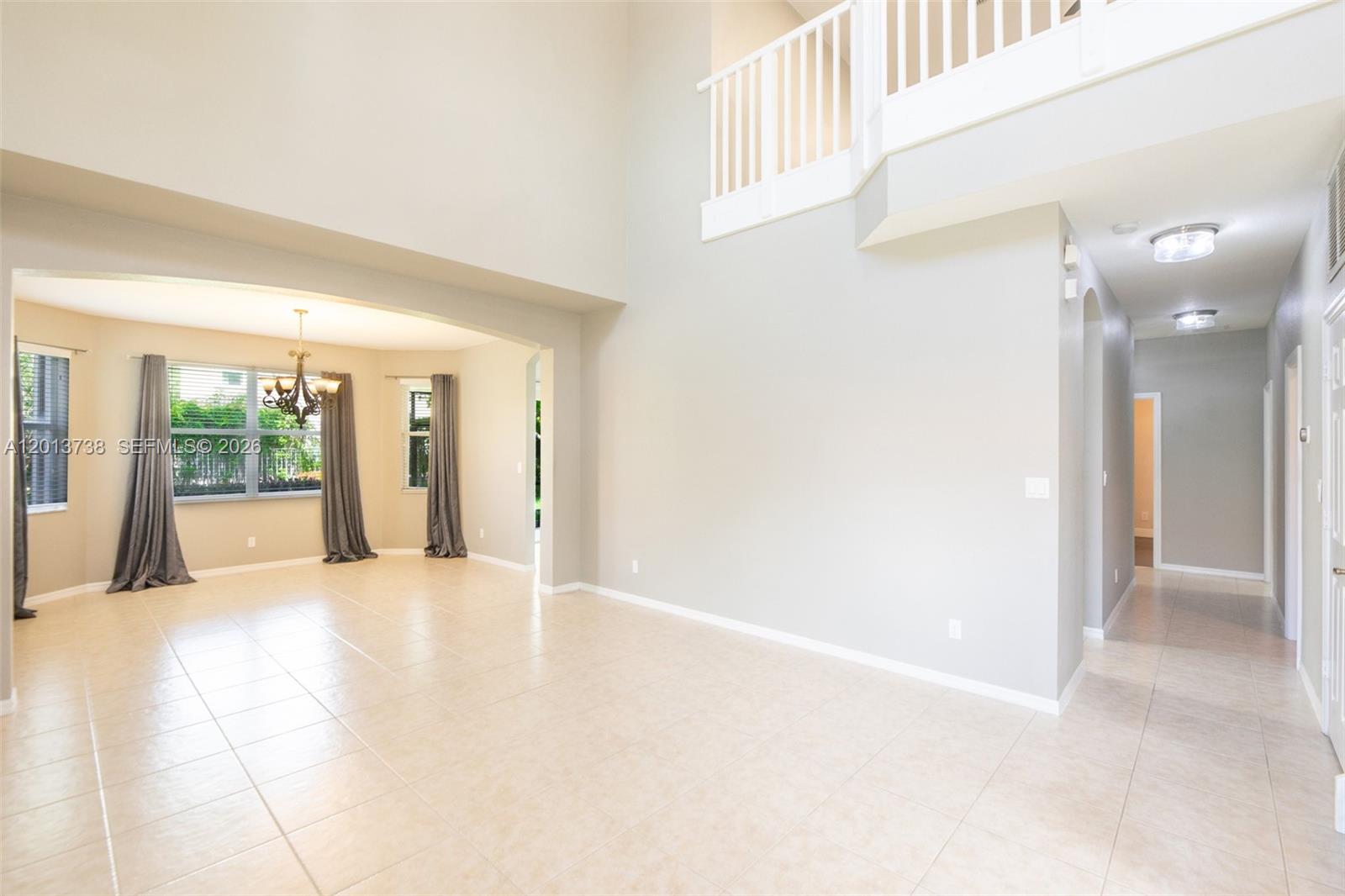 A spacious, high-ceilinged living area features light tile flooring, neutral walls, and a lofted balcony — 4207 W Whitewater Ave, Weston FL 33332, WESTON, FL