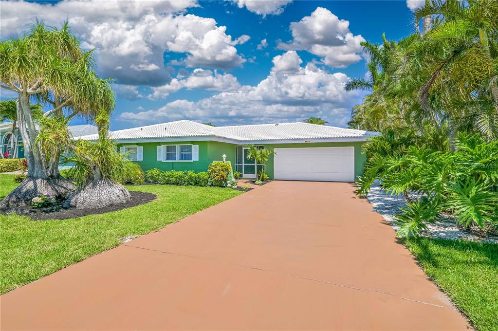 A green single-story house with a white roof and a tan driveway — 4815 SORRENTO COURT, CAPE CORAL, FL