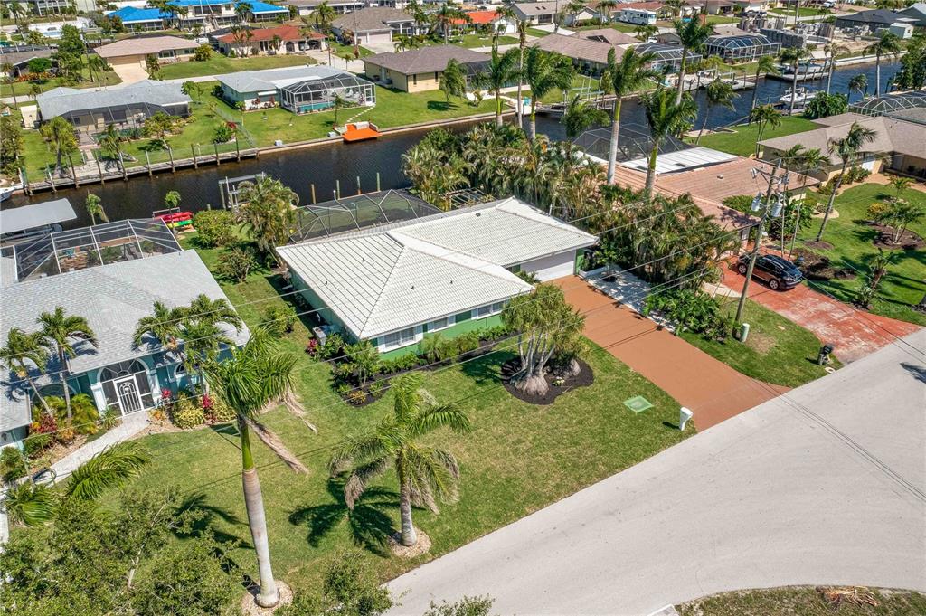 An aerial view shows a single-story house with a white roof and a canal — 4815 SORRENTO COURT, CAPE CORAL, FL