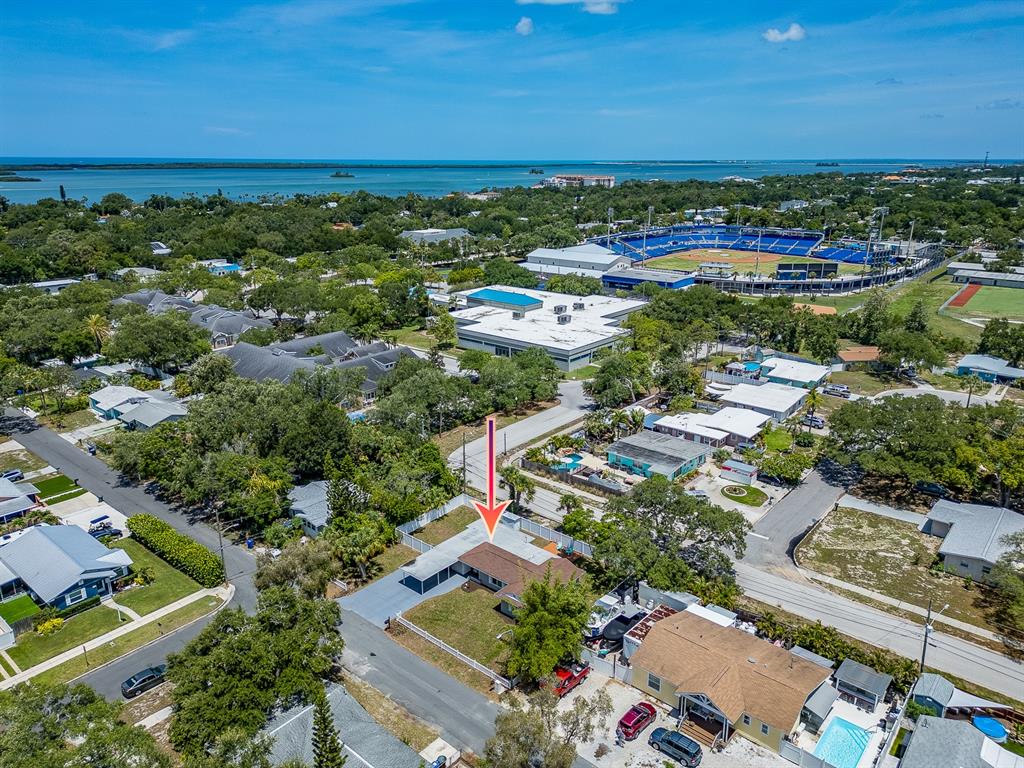 An aerial view shows a residential house with a carport and fenced yard near a stadium — 502 LEXINGTON STREET, DUNEDIN, FL