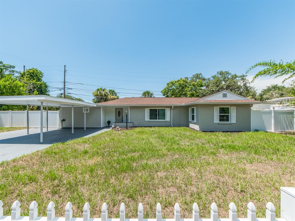 A single-story gray house with a white picket fence and a covered carport — 502 LEXINGTON STREET, DUNEDIN, FL