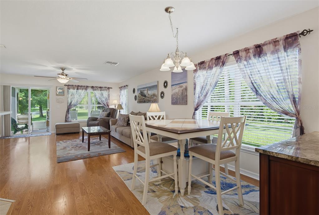 A dining area with a tiled table and chairs sits adjacent to a living room — 2690 SICILY DRIVE, NEW SMYRNA BEACH, FL