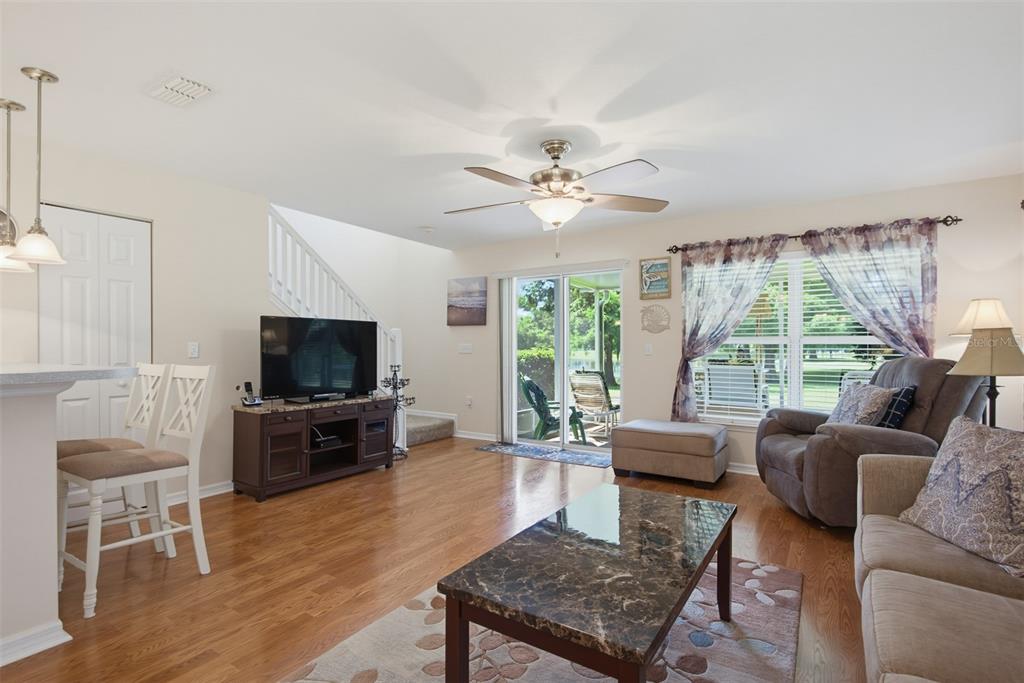 A living room with hardwood floors, a ceiling fan, a sliding glass door, and furniture — 2690 SICILY DRIVE, NEW SMYRNA BEACH, FL