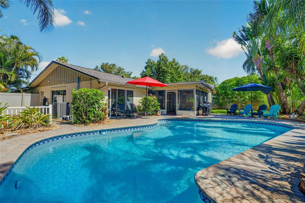 A backyard features a swimming pool, a patio with umbrellas, and a single-story house — 9259 119TH WAY, SEMINOLE, FL