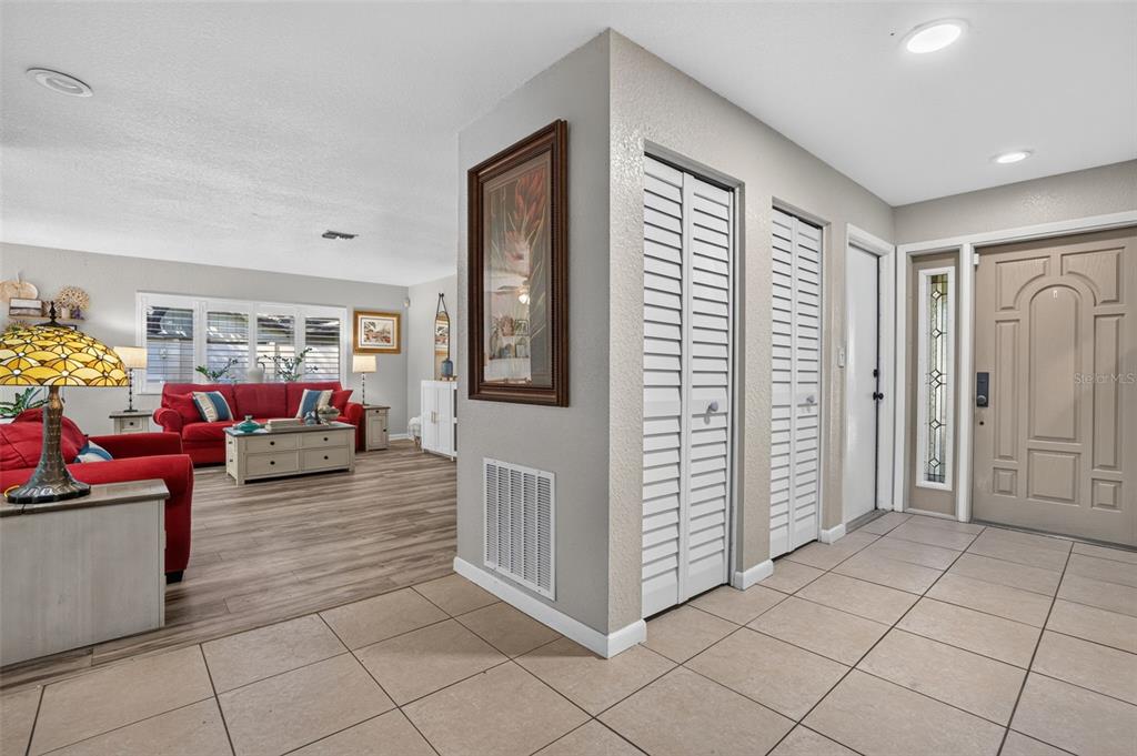 An entryway with tiled floors leads into a living room featuring wood-look flooring and furniture — 9259 119TH WAY, SEMINOLE, FL